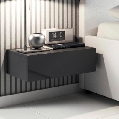 Mesa de cabeceira suspensa cinza escuro com relógio digital, vaso prateado e livro preto, ao lado de cama branca e parede listrada.