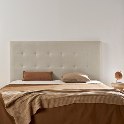 Cama de casal com cabeceira bege, roupa de cama castanha e decoração minimalista