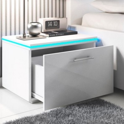 Mesa de cabeceira branca com gaveta aberta e iluminação LED azul, relógio digital, livro e objeto decorativo prateado ao lado de cama
