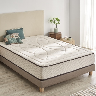 Colchão individual creme com padrão em cama cinza clara com pés em madeira e almofadas decorativas