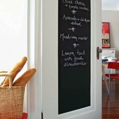 Porta branca com painel negro escrito à giz com ementa, cesto de vime com baguetes, interior com móveis vermelhos