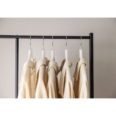Cinco casacos bege pendurados em cabides numa estrutura preta