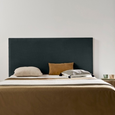 Quarto com cama, cabeceira preta, almofadas bege e castanho, parede branca, mesa de cabeceira e planta