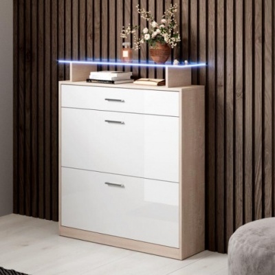 Móvel branco brilhante com três gavetas e decoração com vaso de flores e livros