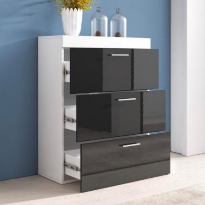 Cômoda branca com gavetas pretas brilhantes, vaso branco com flores amarelas e frascos de vidro sobre a cômoda