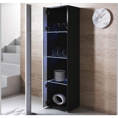 Armário alto preto com prateleiras de vidro iluminadas exibindo louça e copos, junto a parede de madeira clara e relógio marmore