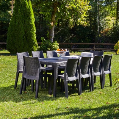 Conjunto de mesa e cadeiras de jardim cinza escuro em espaço exterior com relva e árvores
