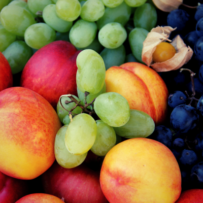 Diversos tipos de frutas, incluindo pêssegos, uvas verdes e pretas, e physalis