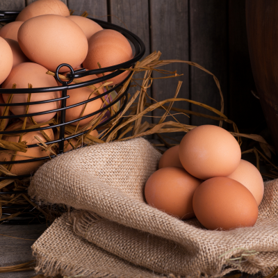 Ovos castanhos numa cesta de arame e sobre tecido de juta