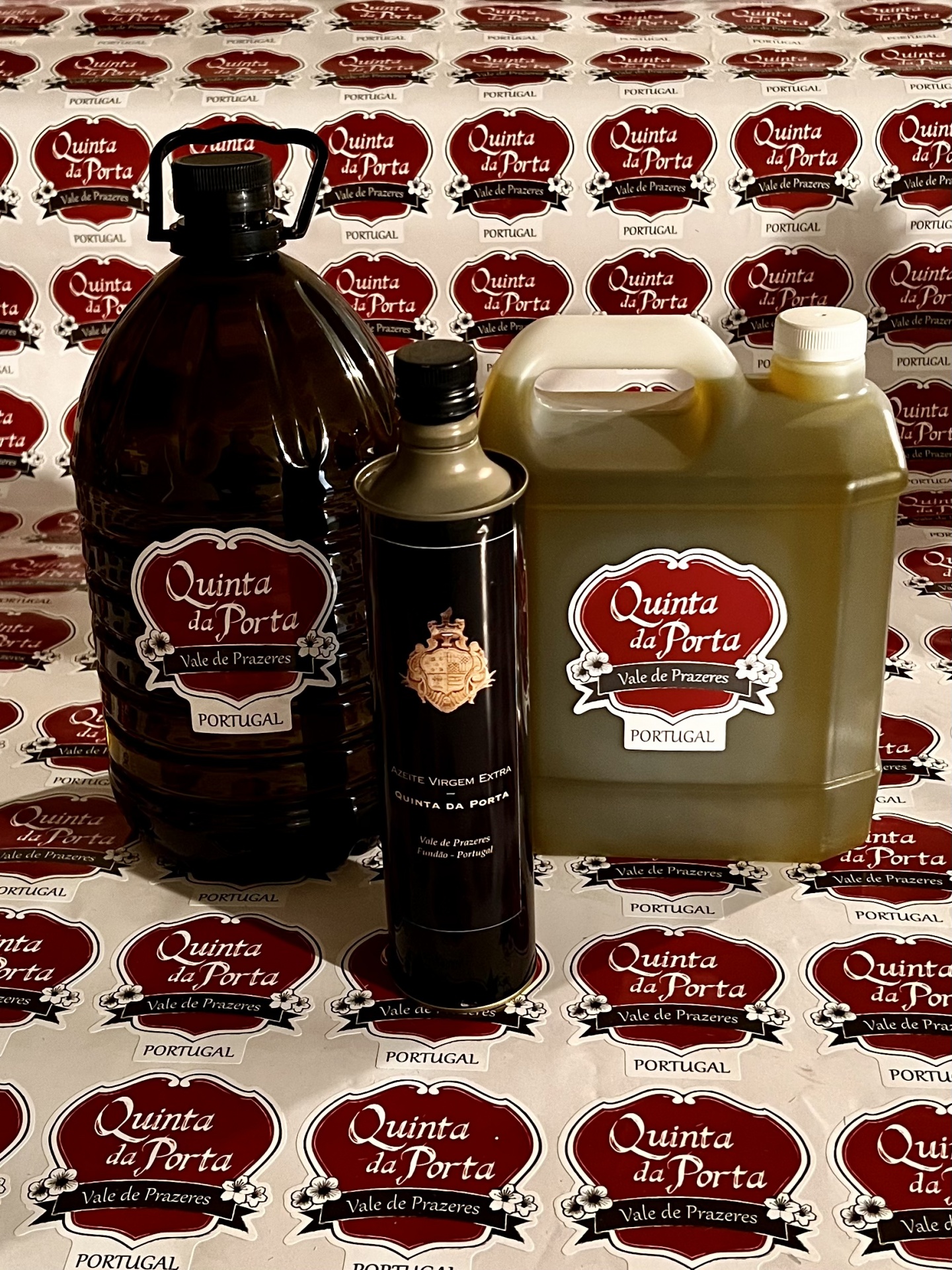 Azeite Virgem Extra - 0,5L Quatro recipientes de azeite Quinta da Porta sobre fundo com padrão do rótulo da marca.