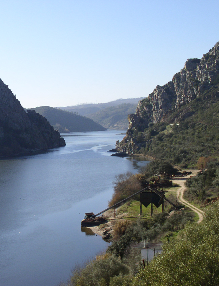 Adega 23 - Branco - PACK 6 Rio largo entre montanhas com vegetação e estrutura metálica à beira da água
