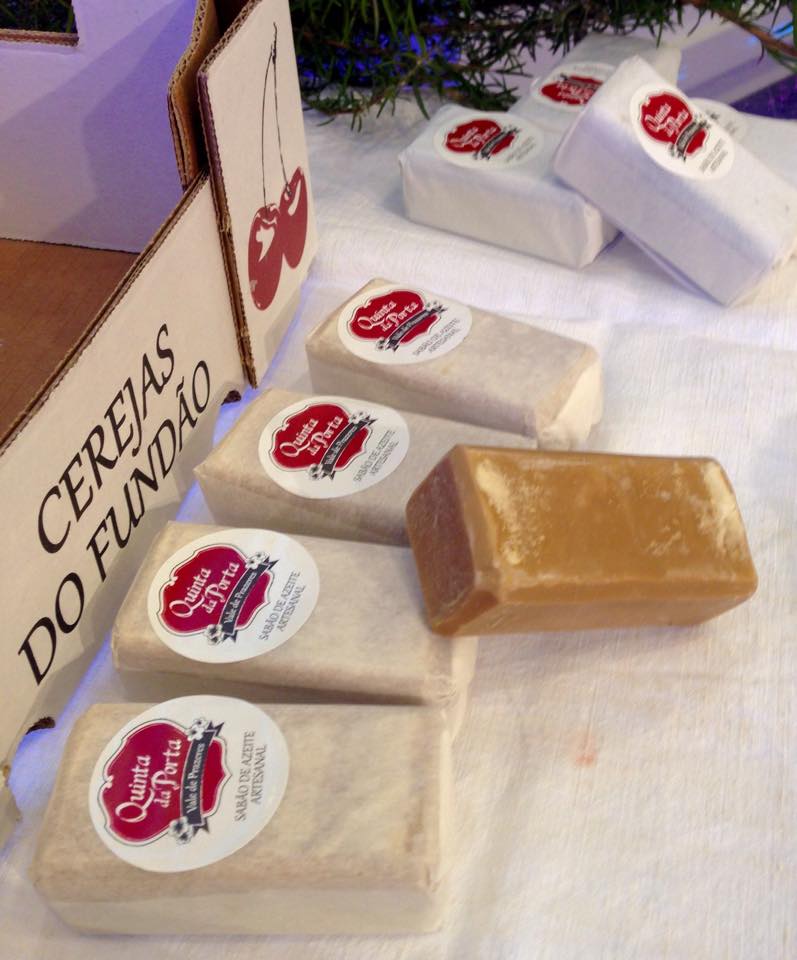 Sabão de Azeite - Artesanal: Cereja (1 un.) Barras de sabonete Quinta Terra's embaladas e uma desembrulhada ao lado de uma caixa de papelão com texto Cerejas do Fundão.