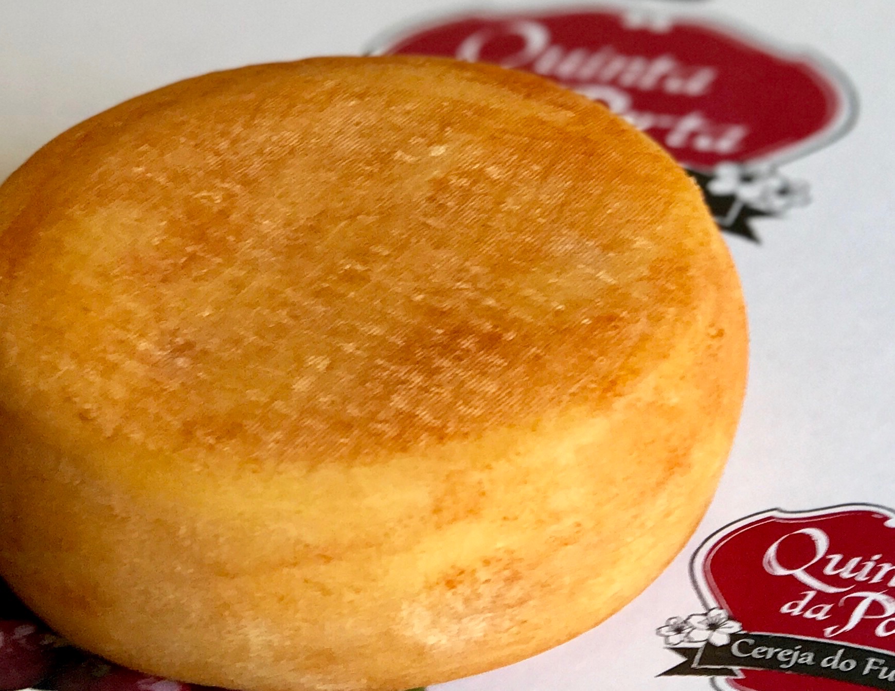 Queijo da Soalheira Queijo redondo amarelo com selo vermelho em fundo branco.