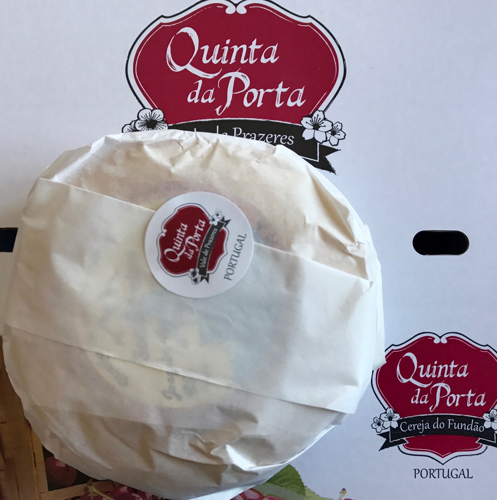 Queijo da Soalheira Produto embrulhado em papel branco com selo 'Quinta da Porta' sobre caixa branca com logo vermelho.