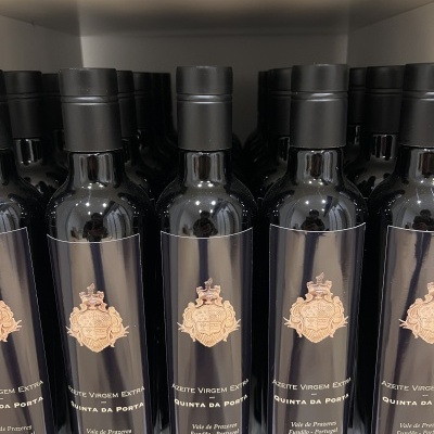 Garrafas de azeite virgem extra com rótulo negro e emblema dourado em prateleira