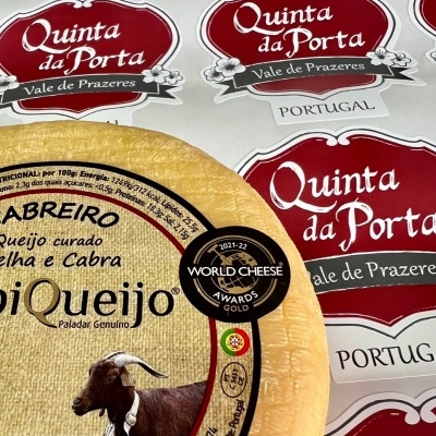 Roda de queijo com etiqueta e várias etiquetas de Quinta da Porta ao fundo