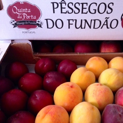 Caixa aberta com pêssegos de várias cores e texto da marca Quinta da Porta