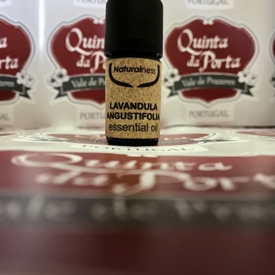 Frasco pequeno de óleo essencial com rótulo e tampa preta sobre superfície com texto Quinta de Portas