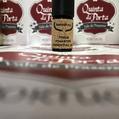 Frasco pequeno de óleo essencial com rótulo de cortiça e caixas ao fundo