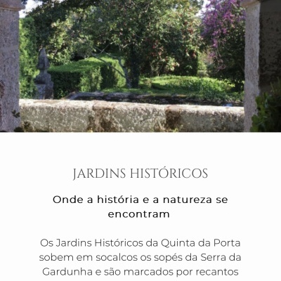 Vista de jardim histórico com árvores, flores roxas e estrutura de pedra em primeiro plano