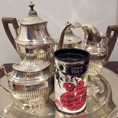 Conjunto de chá em metal prateado com lata colorida de chá à frente