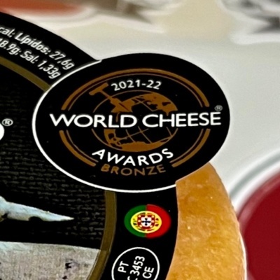 Queijo embalado com etiqueta World Cheese Awards Bronze e bandeira de Portugal