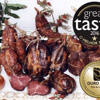 Paio do Lombo com cebolas e alho numa mesa de madeira com medalhas de prémios