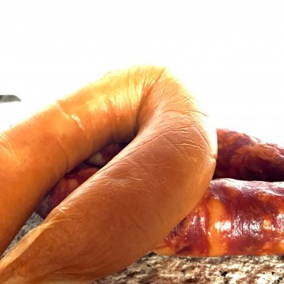 Três enchidos, um laranja claro e dois castanho avermelhados, sobre uma superfície de pedra