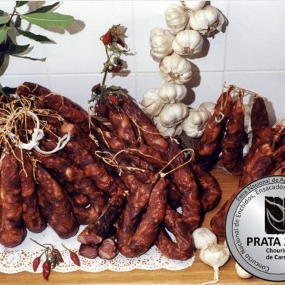 Cachos de chouriço de carne vermelho com cabeças de alho sobre toalha branca e azulejos brancos