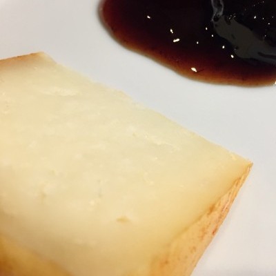 Fatia de queijo com molho escuro num prato branco