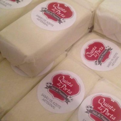 Pacotes de sabão de leite artesanal com etiquetas vermelhas e brancas embalados em papel creme