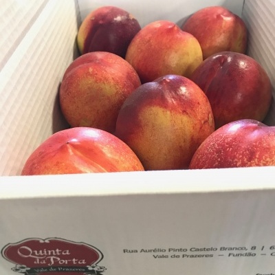Caixa branca com pêssegos vermelhos e amarelos e logo Quinta da Porta