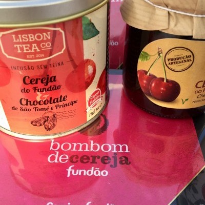 Lata de chá e frasco de compota com rótulos de cereja sobre fundo cor-de-rosa com texto