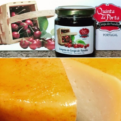 Frasco de compota de cereja e queijo amarelo cortado em superfície cinza.