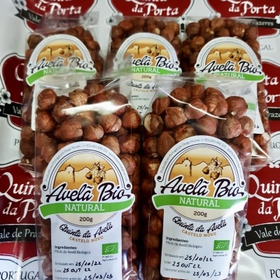 Pacotes de avelãs naturais com rótulos brancos e verdes sobre etiquetas Quinta da Porta Portugal.