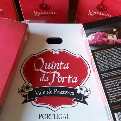 Embalagens vermelhas de bombons e caixa branca da Quinta da Porta com texto em português