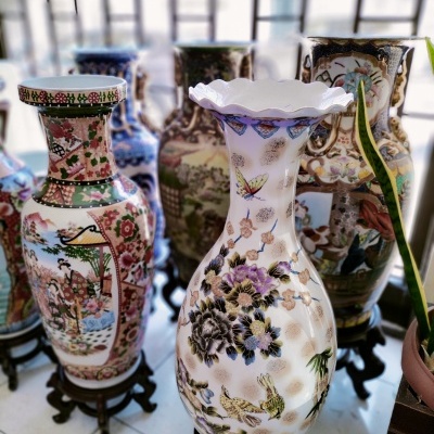 Vasos de cerâmica coloridos com padrões florais e animais sobre suportes de madeira