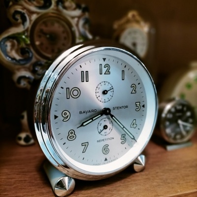 Relógio despertador redondo prateado com mostrador branco e números pretos