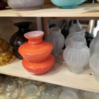 Lâmpadas decorativas de vidro em diferentes cores e texturas sobre prateleiras de madeira