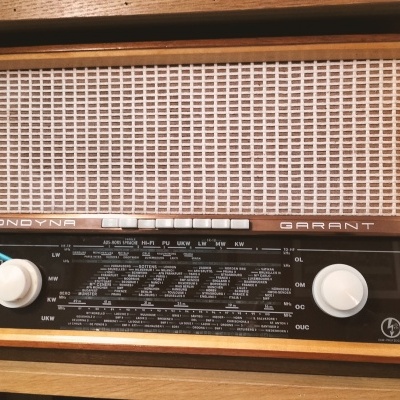 Rádio vintage de madeira com painel frontal em tecido bege e botões brancos