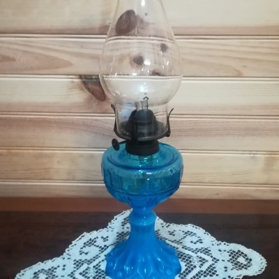 Lampião a petróleo azul com cúpula transparente em fundo de madeira