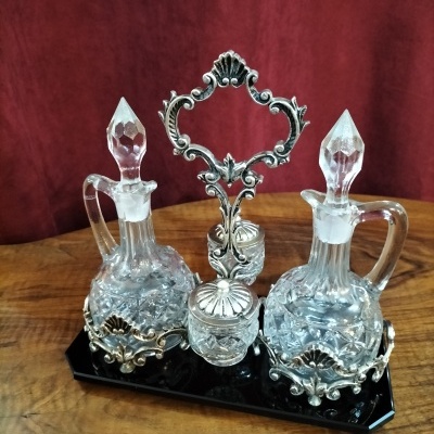 Conjunto vintage de garrafas e frasco em vidro e metal prateado sobre base preta