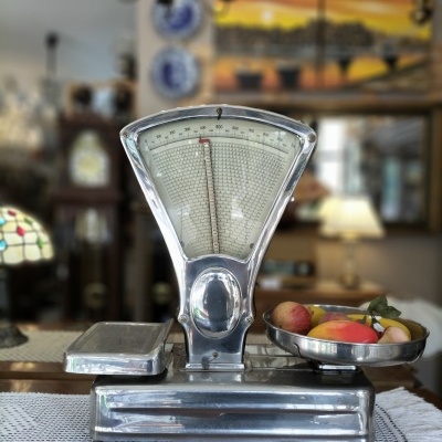 Balança mecânica vintage em metal prateado com frutas em uma bandeja