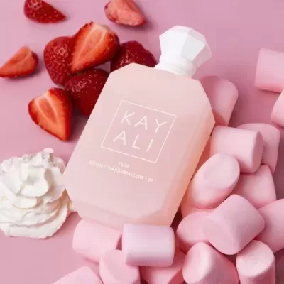 Frasco de perfume rosa claro com texto KAY ALI e marshmallows cor-de-rosa com morangos e chantilly