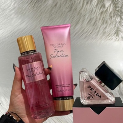 Frascos de perfumes e loção Victorias Secret Pure Seduction e perfume Prada Paradoxe sobre superfície branca felpuda.