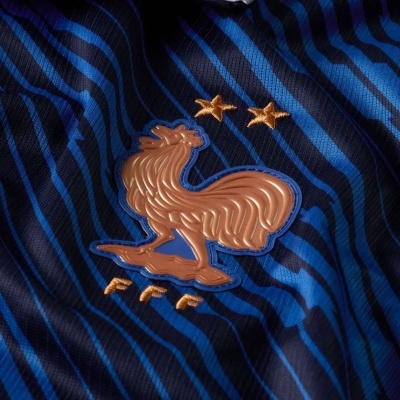 Camisola azul com riscas pretas e emblema dourado de um galo com duas estrelas.