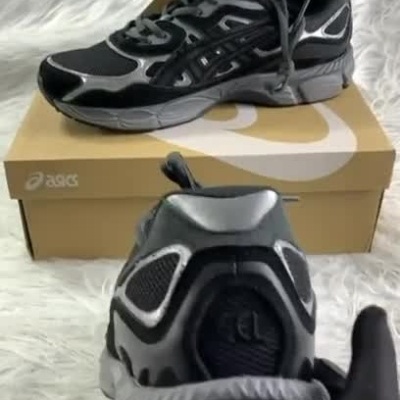 Ténis pretos e cinza Asics vistos de vários ângulos sobre fundo branco.