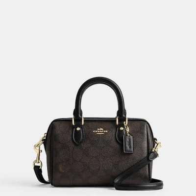 Bolsa de mão COACH castanha e preta com detalhes dourados.