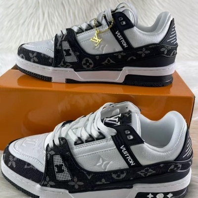 Sapatilhas brancas e pretas Louis Vuitton com padrão Monogram preto, sobre caixa laranja.