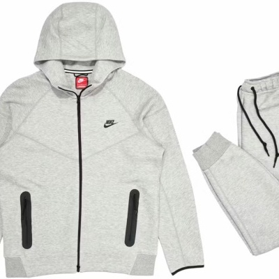 Conjunto desportivo cinzento claro Nike com casaco com capuz e calças com cordão preto.